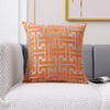 An orange and gray geometric patterned lumbar pillow cover resting on a light gray sofa.