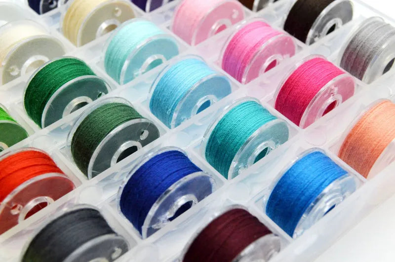 A collection of assorted sewing thread bobbins in various colors and shades arranged in a clear plastic container.