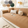 A beige anti-slip fabric sofa cushion cover with a geometric pattern and decorative pillows on a light-colored sofa.