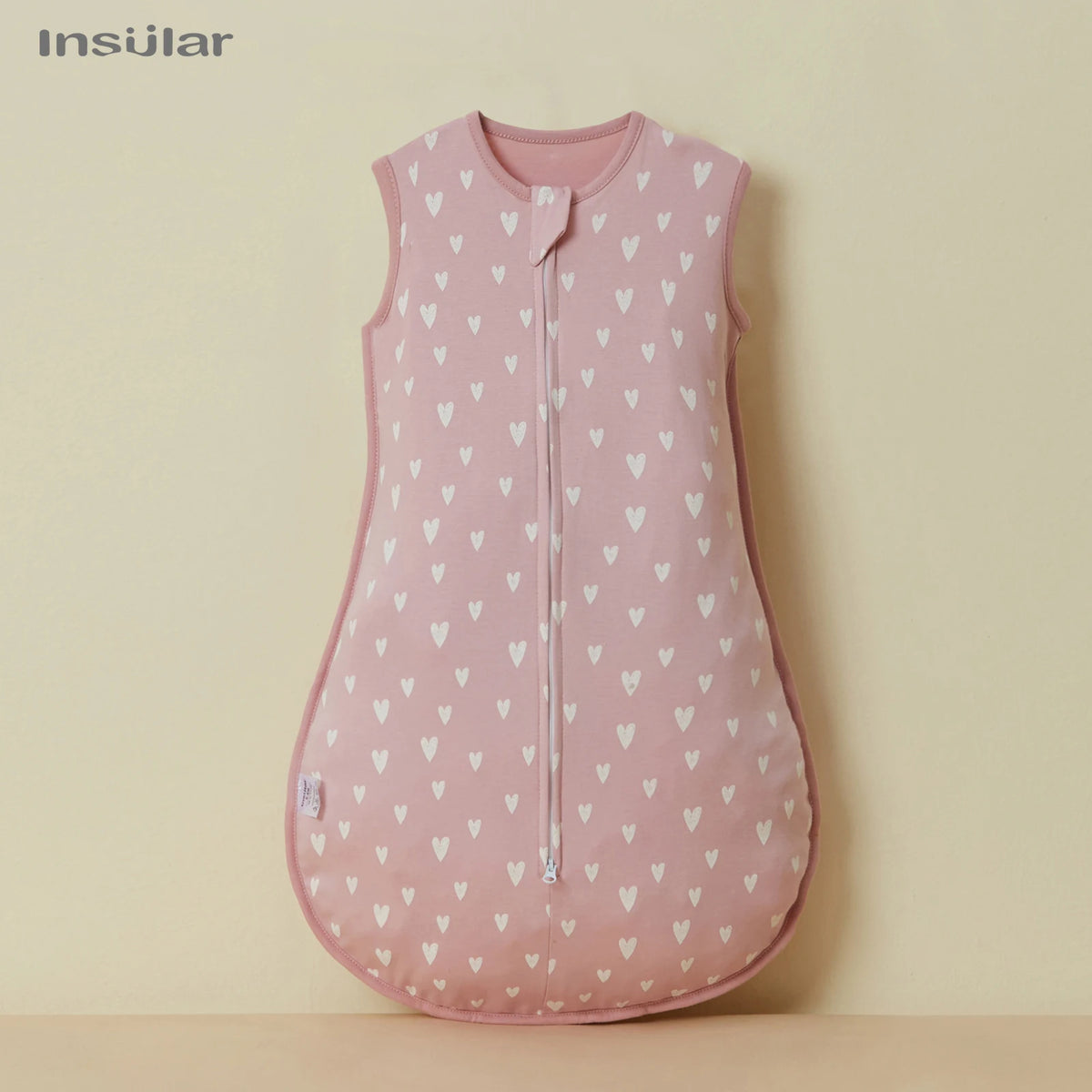 A pink unisex cotton sleep sack for baby and toddler hanging against a light background.