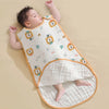 A baby is lying on a white sleeping bag featuring lion patterns and greenery, resting on a beige surface.