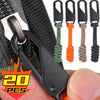 A set of five black detachable zipper pulls with colored cord ties shown against a black fabric background.