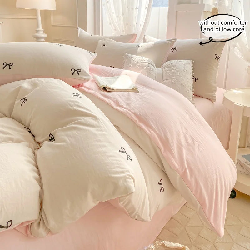 A pink and white bedding set featuring a duvet cover, pillowcases, and a decorative throw with bowknot embroidery.