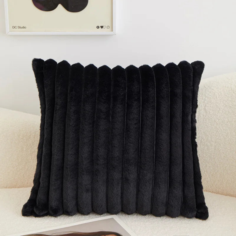 A black faux fur stripe decorative throw pillow cover displayed on a light-colored sofa.