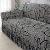 A gray pleated fabric sofa cover featuring a black leafy pattern on a sofa in a living room.