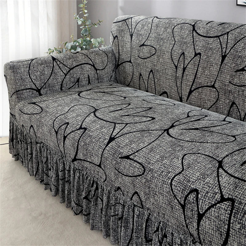 A gray pleated fabric sofa cover featuring a black leafy pattern on a sofa in a living room.