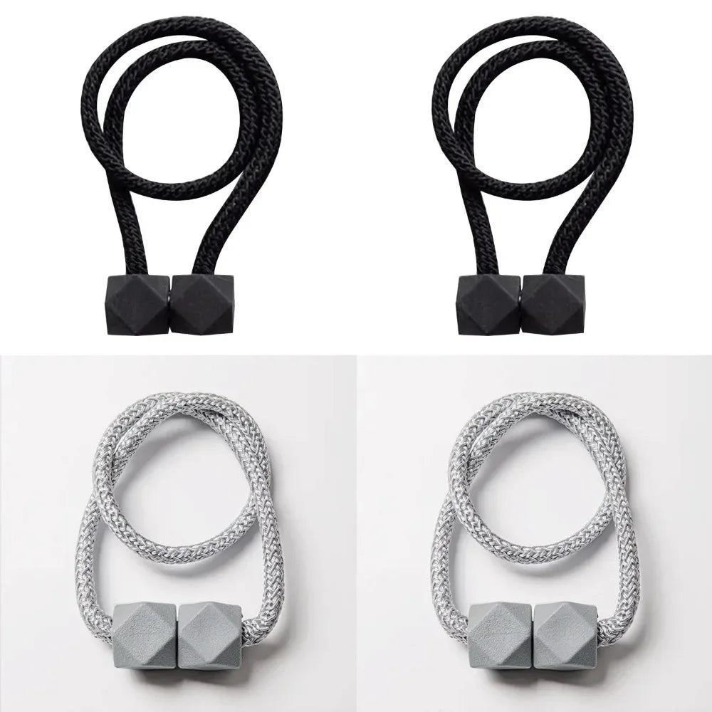A set of four black magnetic curtain tiebacks, including two looped and two flat, silver-toned versions.