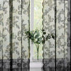 Vintage floral lace curtain panel with black vertical stripes and a vase of green foliage
