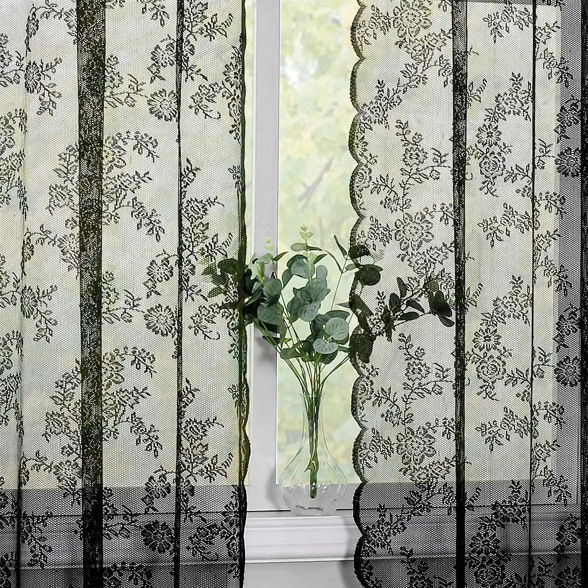 Vintage floral lace curtain panel with black vertical stripes and a vase of green foliage