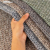 A hand is holding a textured gray and white fabric, likely a universal pet-proof sofa cushion cover.