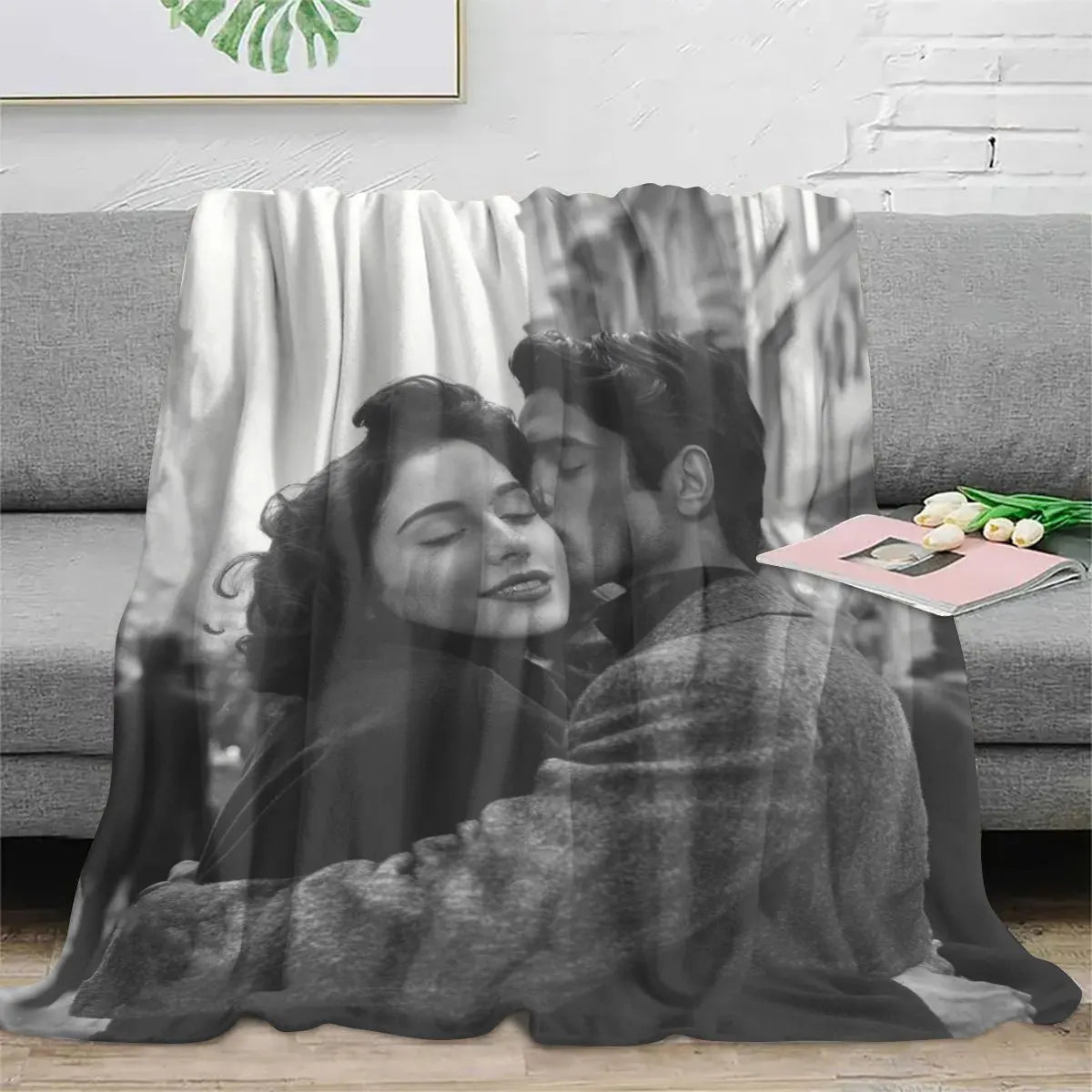 A couple embracing in a black and white photo blanket against a blurred background.