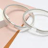 Silver metal sleeve garters or adjustable arm bands lying on a pink and brown surface.