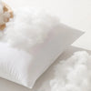 A white breathable square core cushion with fluffy white material and a wooden scoop visible.