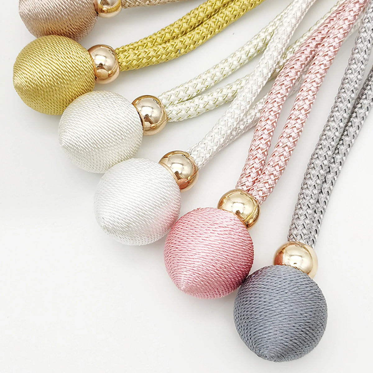 A collection of adjustable French ball curtain tiebacks in various colors including gold, lime green, white, pink, and gray.