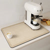 A white espresso machine is placed on a beige kitchen drain mat on a white countertop.