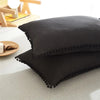 A set of black duvet covers featuring pom-pom trim, displayed on a light surface.