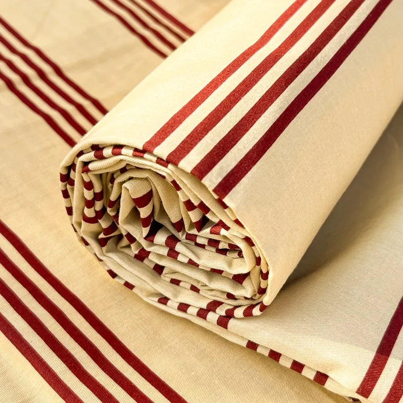 Rolled organic cotton bedding set featuring red and white stripes on a beige background
