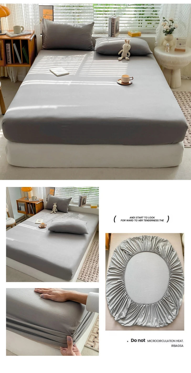 A fitted bed sheet in light gray fabric is shown folded on a bed, with a hand demonstrating its texture.