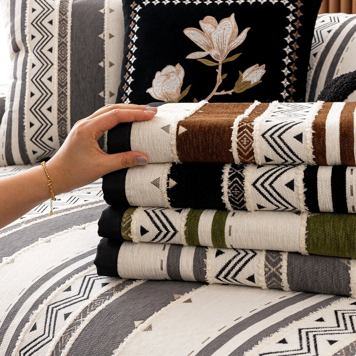 Stack of bohemian chenille sofa cushion covers featuring geometric patterns in brown, black, white, and olive green.