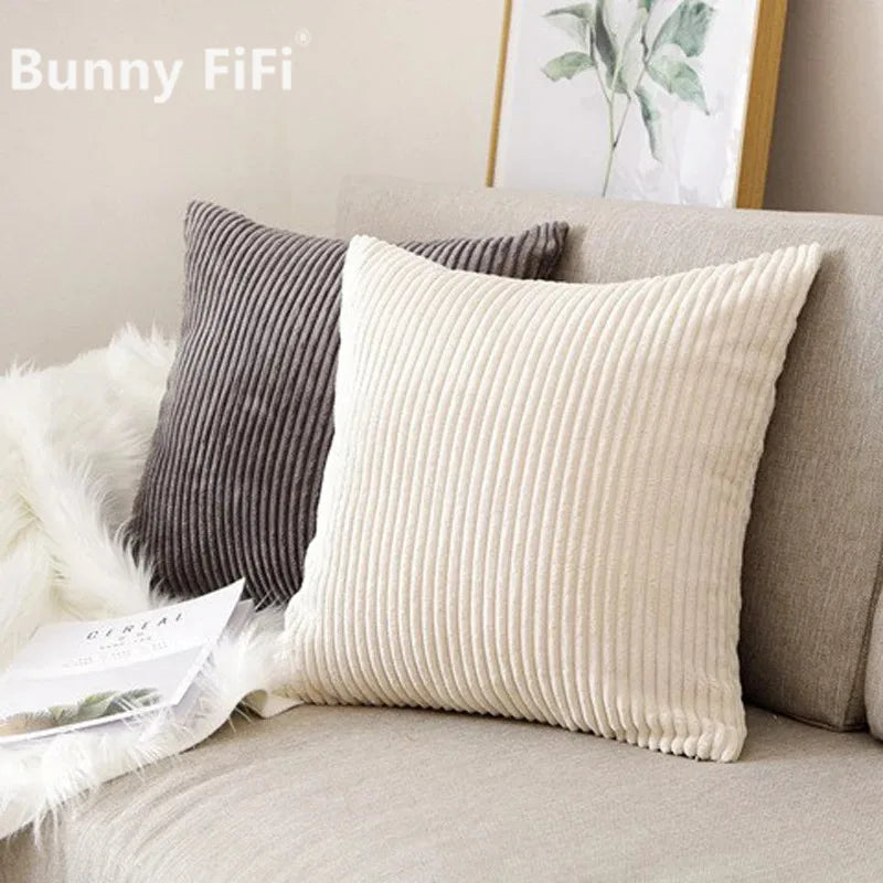 A cream ribbed throw pillow resting on a light gray sofa next to a dark gray striped pillow.