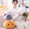 A young woman is holding a white cat plush pillow and a gray cat plush cushion in a bright indoor setting.