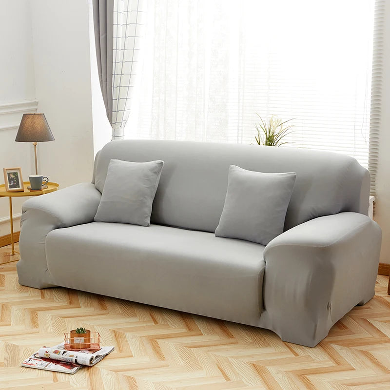 A light gray elegant faux silk sofa cover displayed on a modern sofa in a bright room.