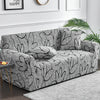 A gray elastic sofa cover protector featuring a black floral print on a sofa.
