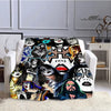 A printed flannel travel blanket featuring a collage of stylized faces and dark artwork.