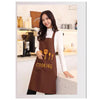 A woman wearing a brown waterproof oil-proof PVC kitchen apron while cooking in a bright kitchen setting.