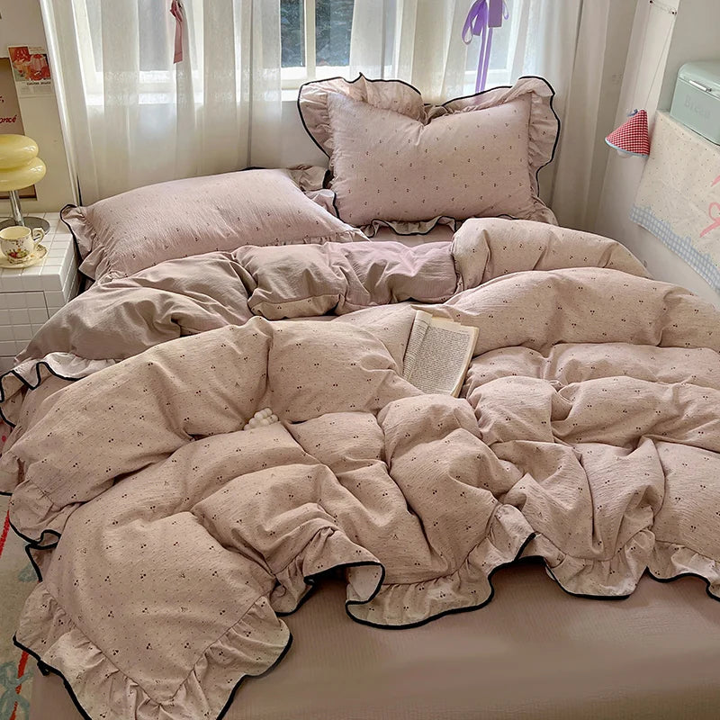 A beige floral bedding set with ruffled edges is displayed on a bed next to a window.