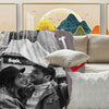 A couple smiling while looking at a map on a flannel blanket in a bright room.