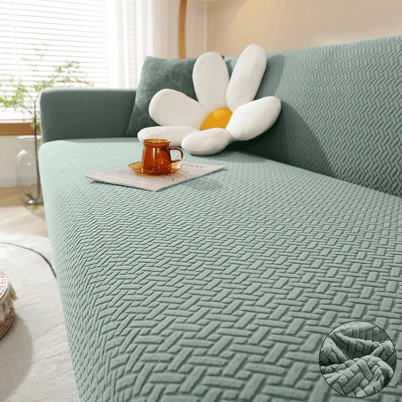 A teal textured sofa cover featuring a white flower cushion and an orange mug on a light-colored sofa.