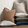 A stack of linen fringe throw pillow covers in beige, cream, and deep blue colors.