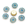A collection of twelve round, blue and clear rhinestone crystals set in gold-toned metal bezels.
