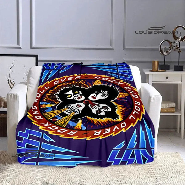 A purple and blue printed flannel travel blanket featuring a black and white rock design on an orange circle.