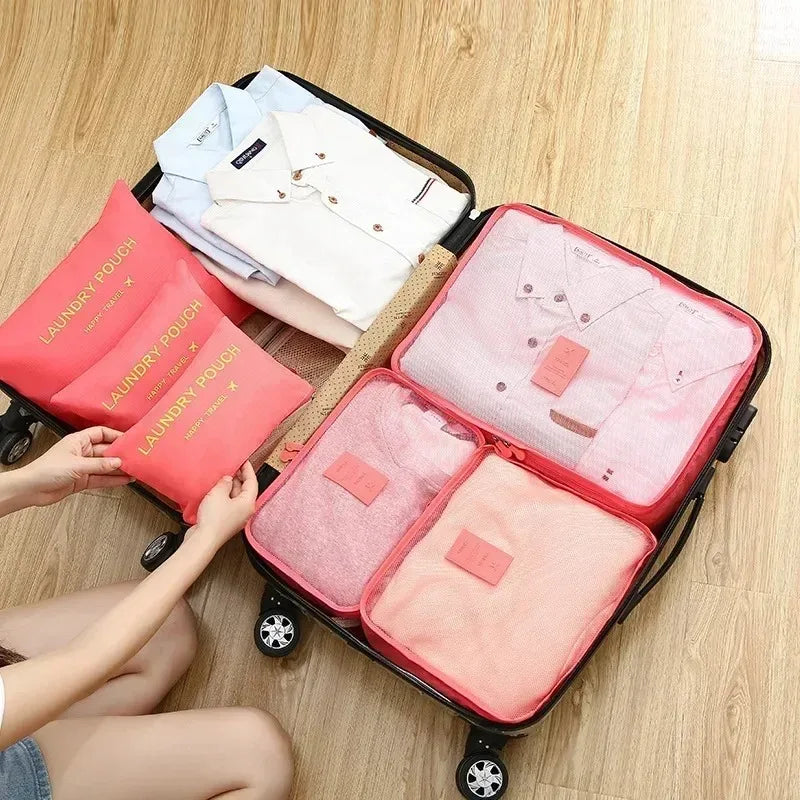 A pink and white travel packing cubes set is shown inside a black rolling suitcase.