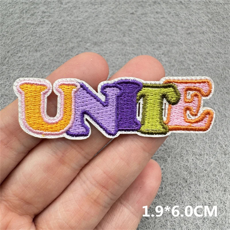 Embroidered patch spelling the word UNITE in various pastel colors on a hand