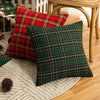 A set of two plaid decorative throw pillows in red and green tartan fabric resting on a light rug.