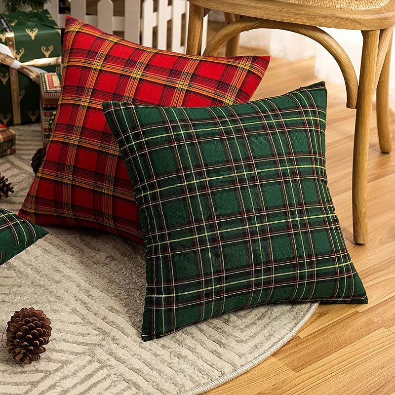 A set of two plaid decorative throw pillows in red and green tartan fabric resting on a light rug.