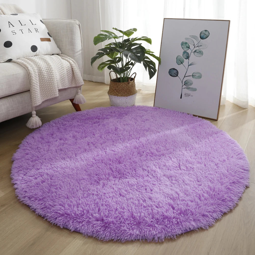 A fluffy purple shaggy round area rug placed on a light wood floor next to a sofa and a potted plant.