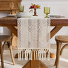 Beige boho hand-woven table runner displayed on a wooden table with natural decor.