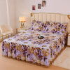 A bed featuring a luxury floral bed skirt with purple and beige patterns protecting the mattress.