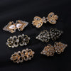 A collection of vintage swirl clip brooches featuring gold-toned metal and clear stones, displayed against a black background