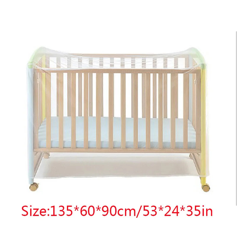 A wooden crib with a protective mesh and clear plastic mosquito net covering the sides.