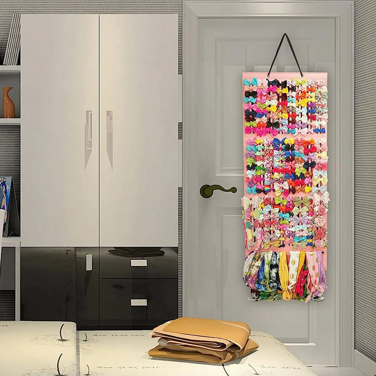 A white cabinet with a glass door and a hanging rack filled with colorful hair clips and accessories.