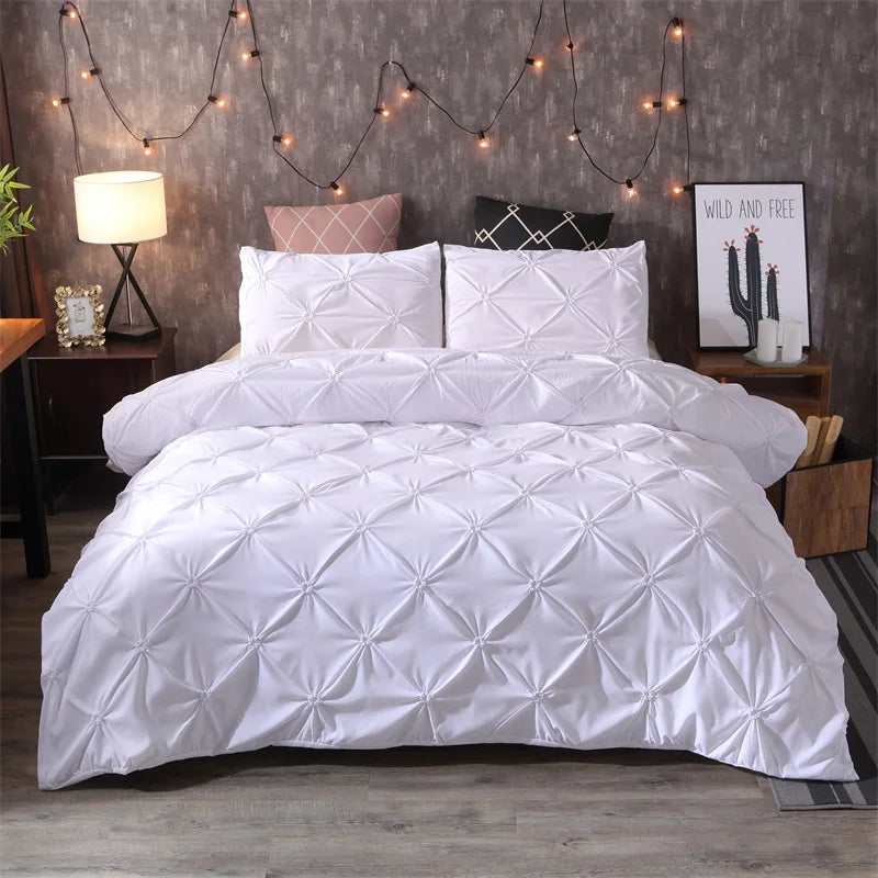 White quilted bedding set with gray accents displayed on a bed against a textured wall.