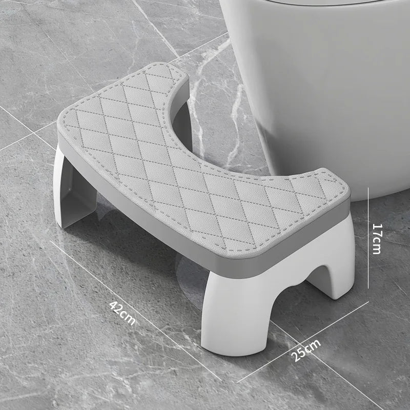 A gray adjustable adult toilet squat stool with a diamond-patterned seat is shown on a tile floor.