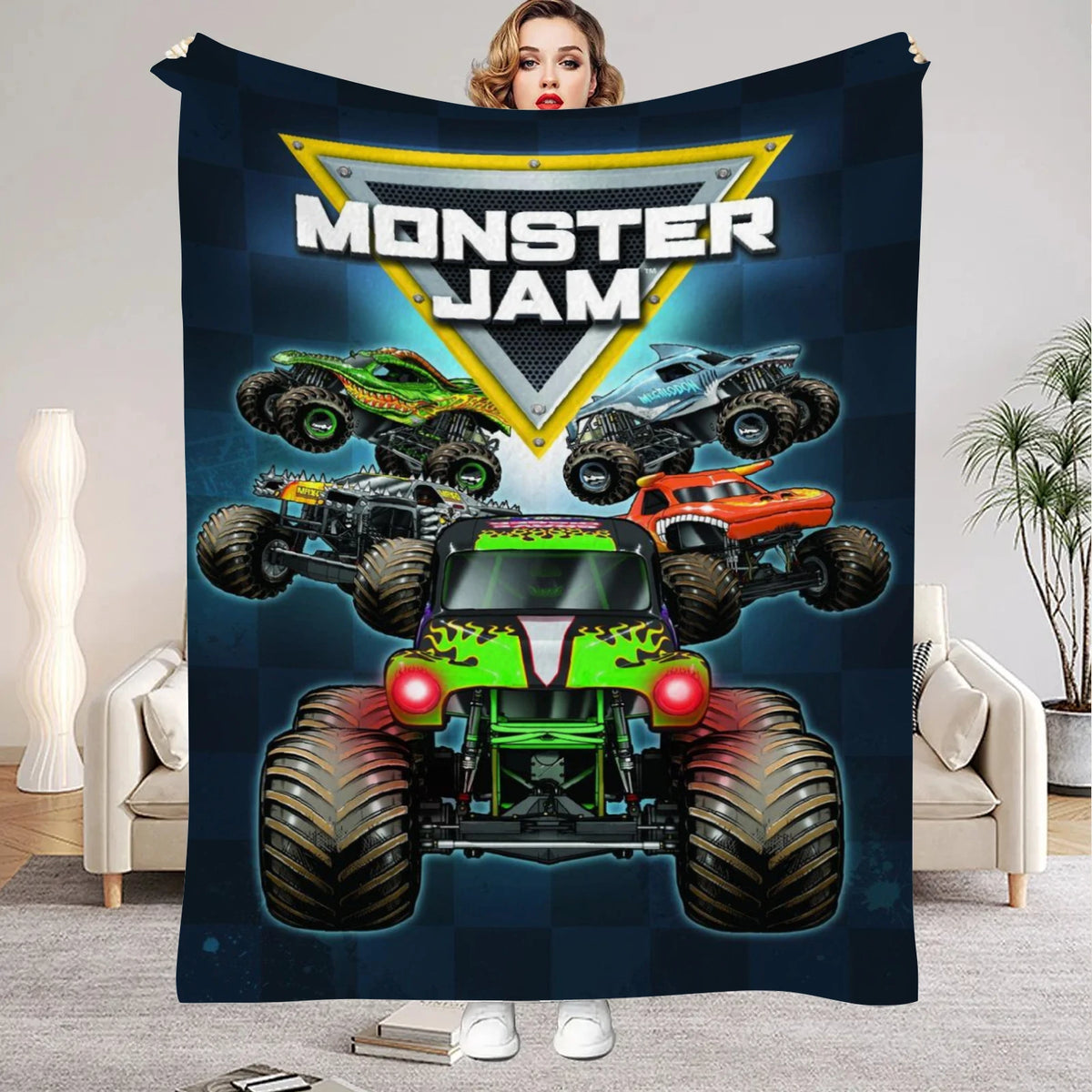 A dark blue blanket featuring a Monster Jam logo and several monster trucks against a dark background.