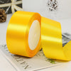 Roll of bright yellow satin ribbon with white center, displayed on a white surface.