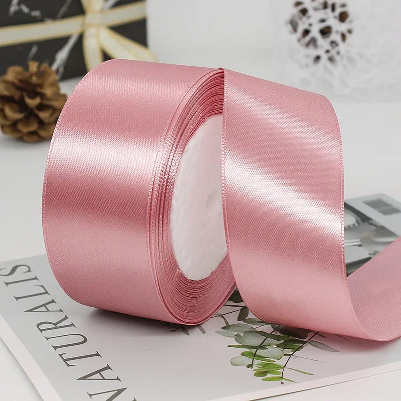 Pink satin ribbon rolled and unrolled, showing the smooth texture and decorative trim.